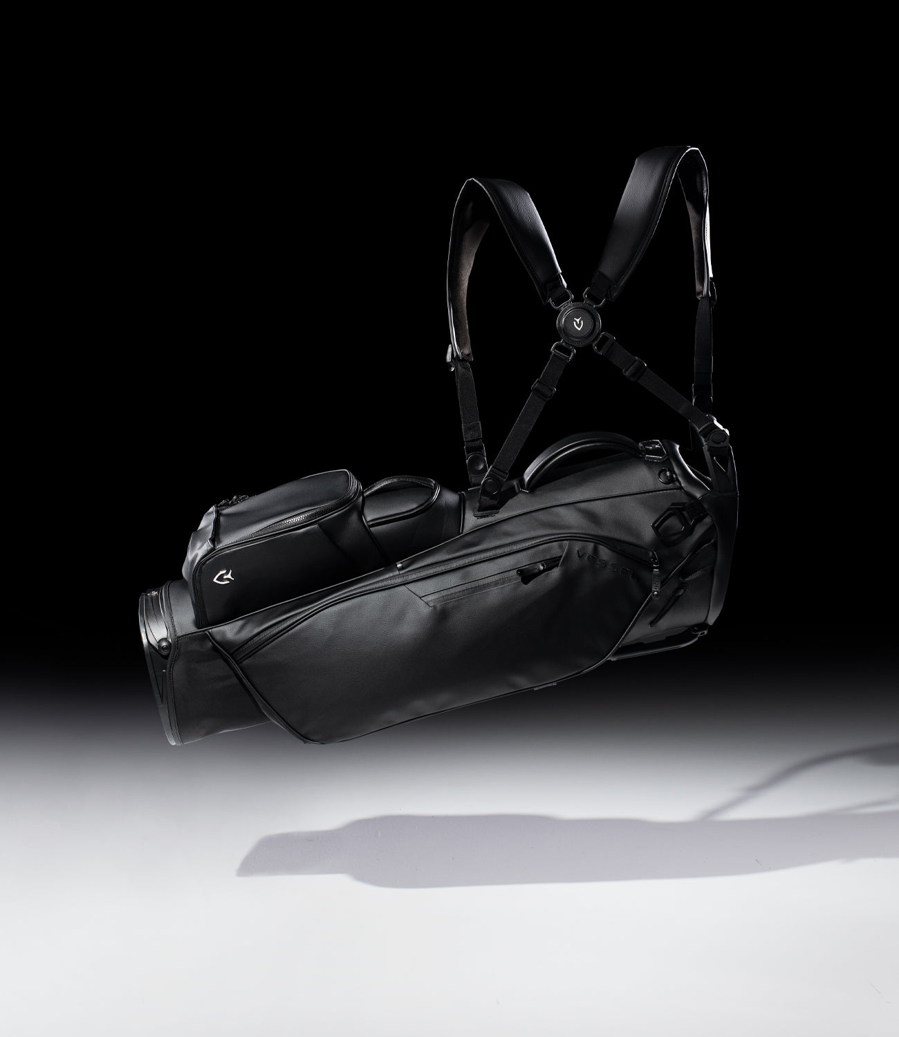 Floating black leather golf stand bag in black studio with gray flooring