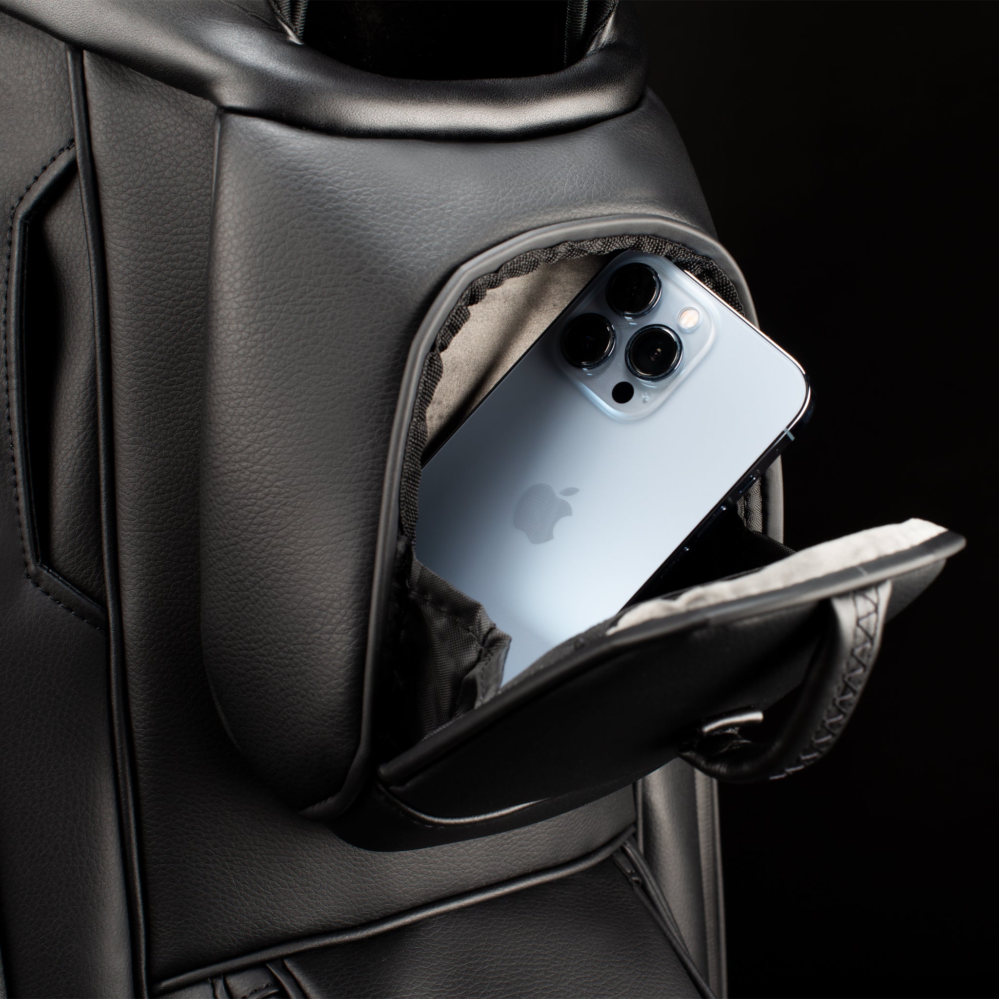 Close up magnetic pocket on black leather golf cart bag with phone sticking out