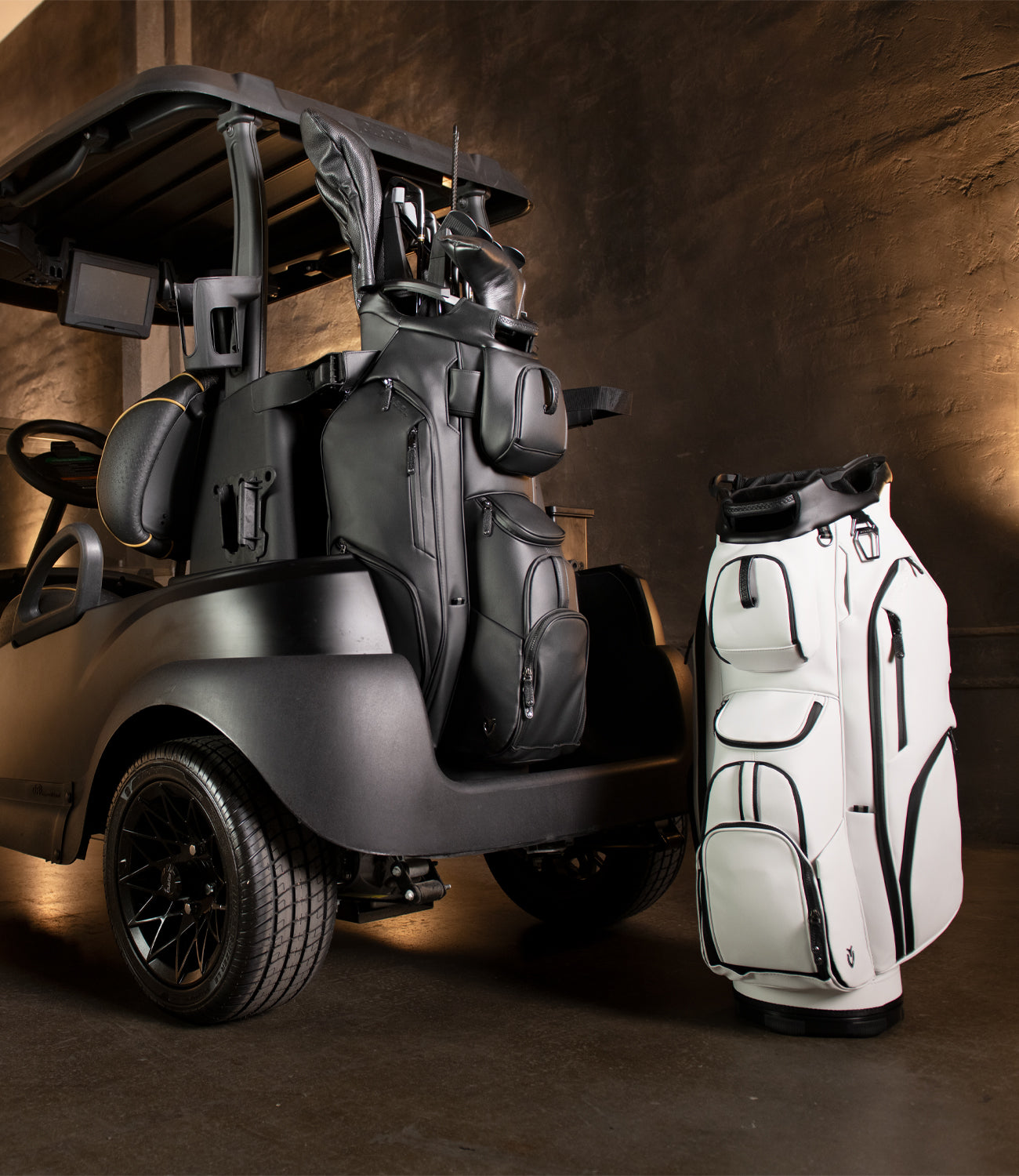 Black leather cart bag on the back of a black golf cart with a while golf cart bag next to it