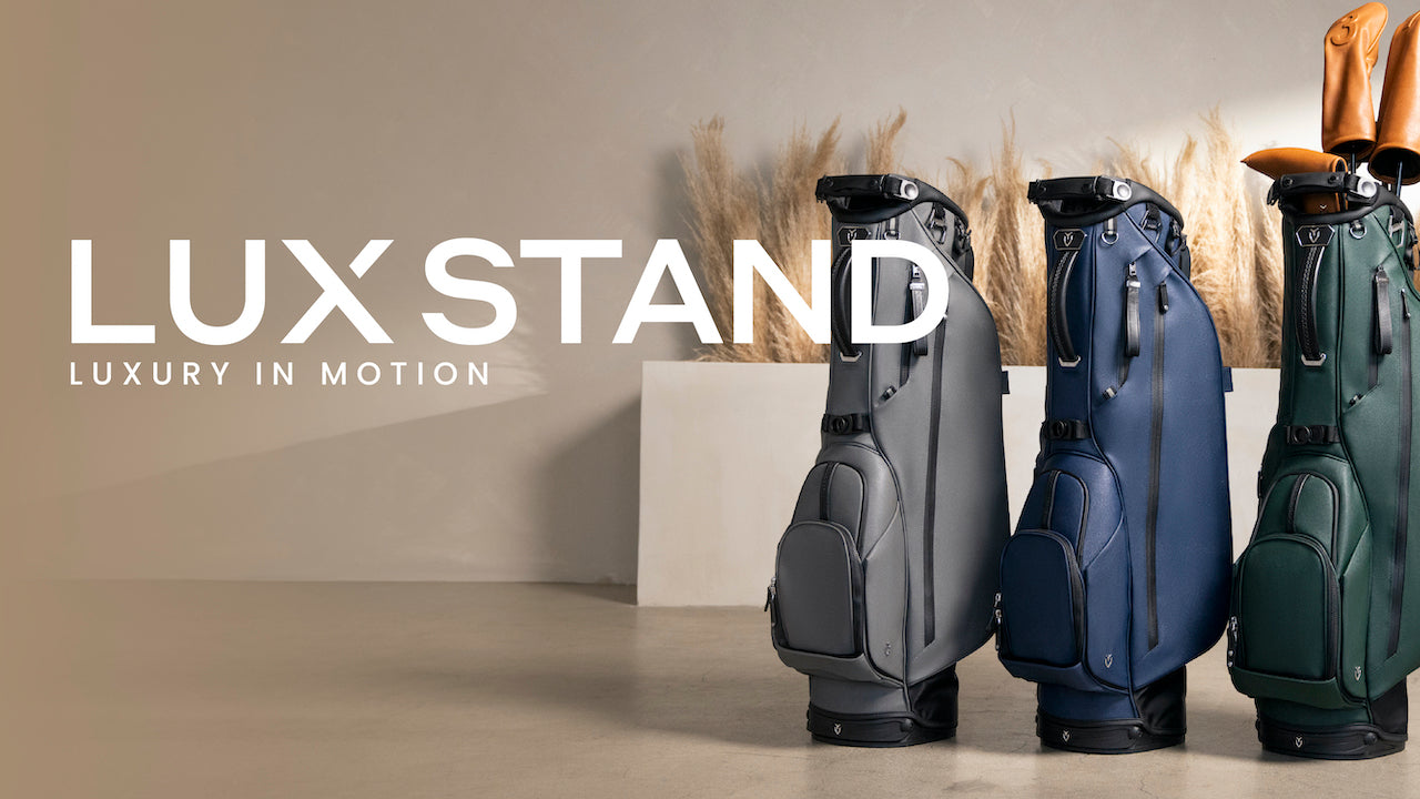 A green, a navy, and a grey Lux Stand leather golf bag in a taupe colored room