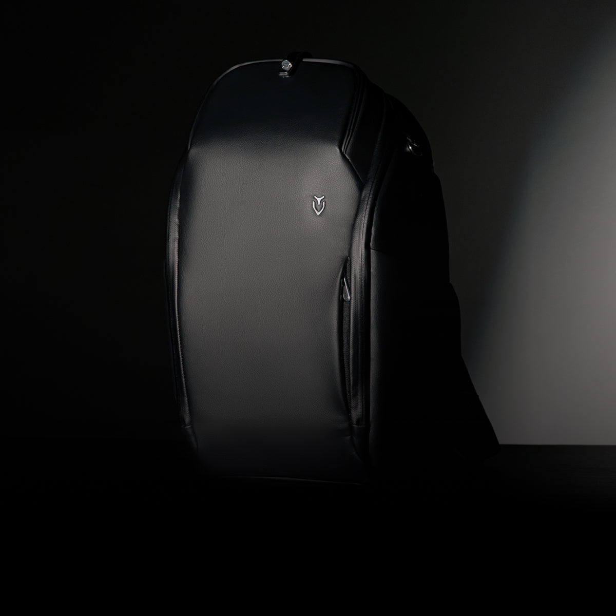 Black leather travel backpack against a black background