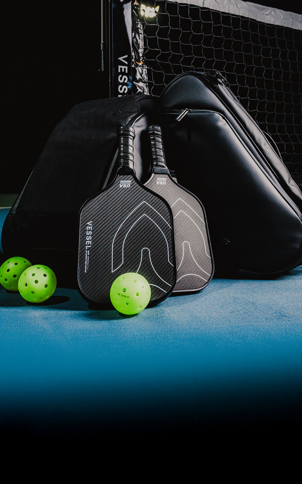 Carbon pickleball paddles leaned against leather pickleball paddle bags with 3 pickleballs on the ground