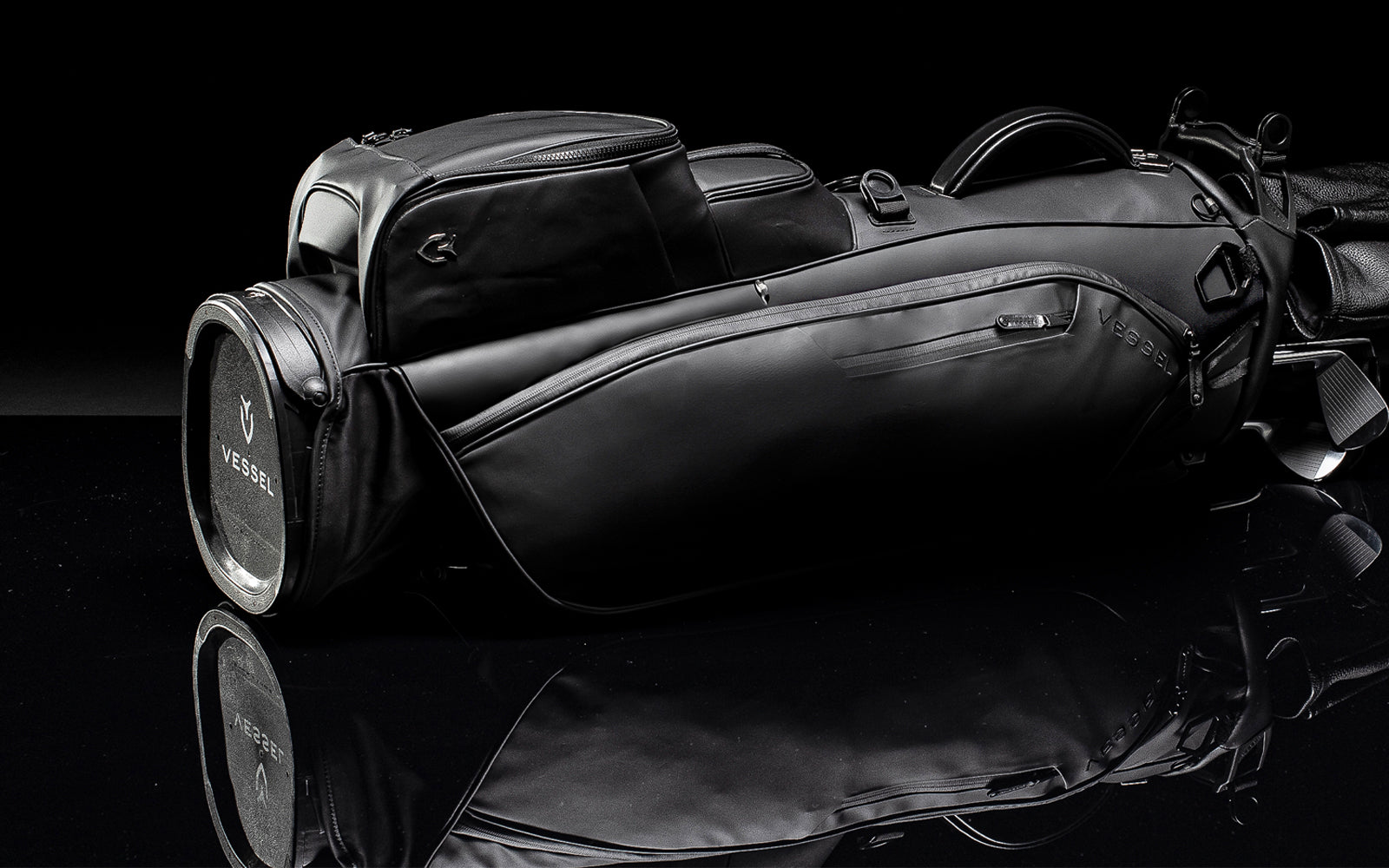 Black golf stand bag laying on ground with black background and reflection 