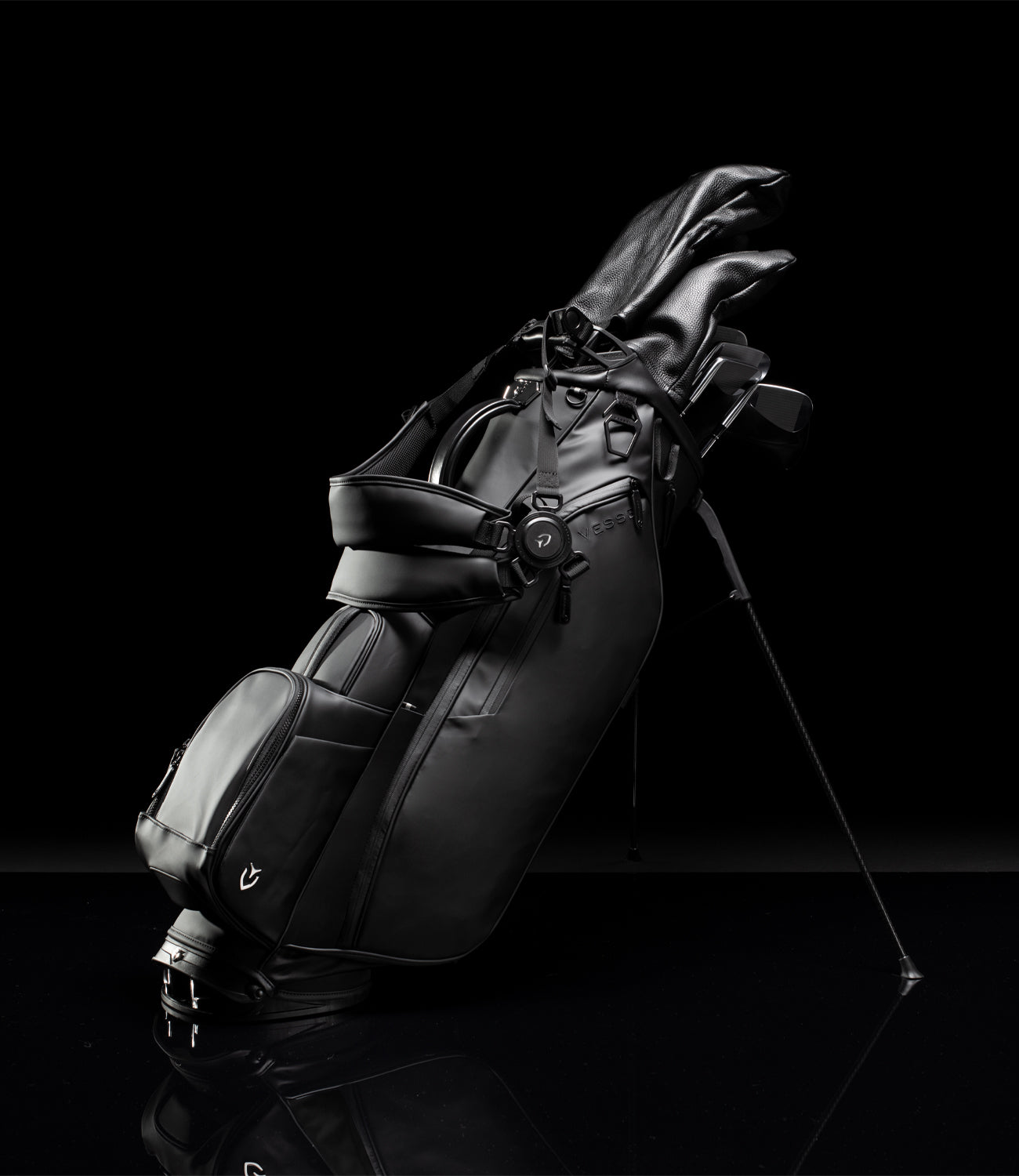 Black leather golf stand bag with strap and clubs in black studio