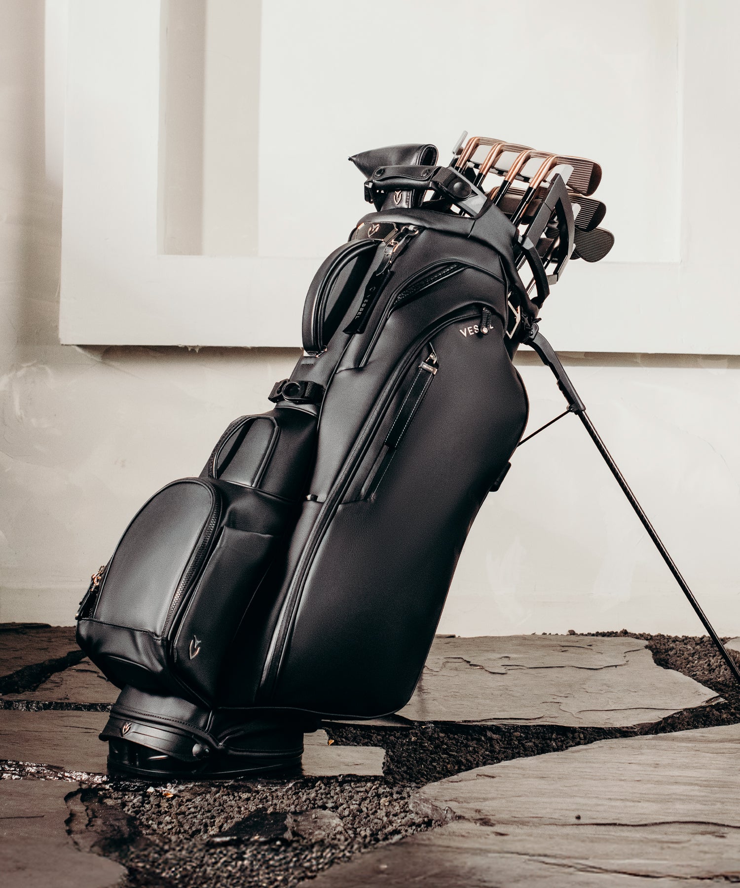 Black leather golf bag with clubs on a stone path