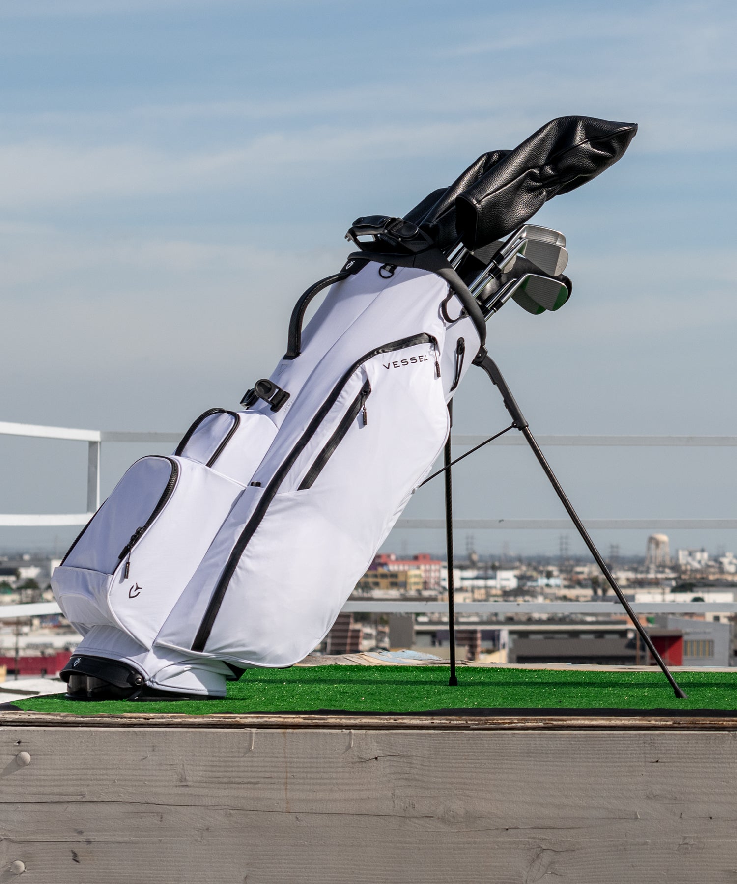 White golf bag on rooftop with golf clubs and black leather headcovers