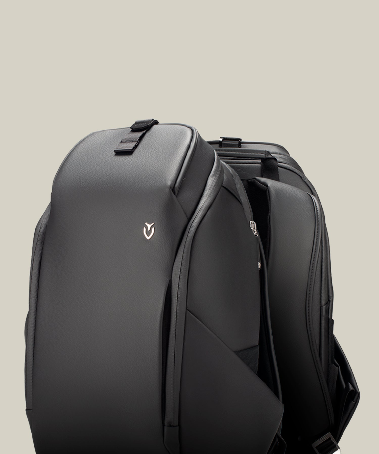 Two PrimeX black backpacks against a taupe background