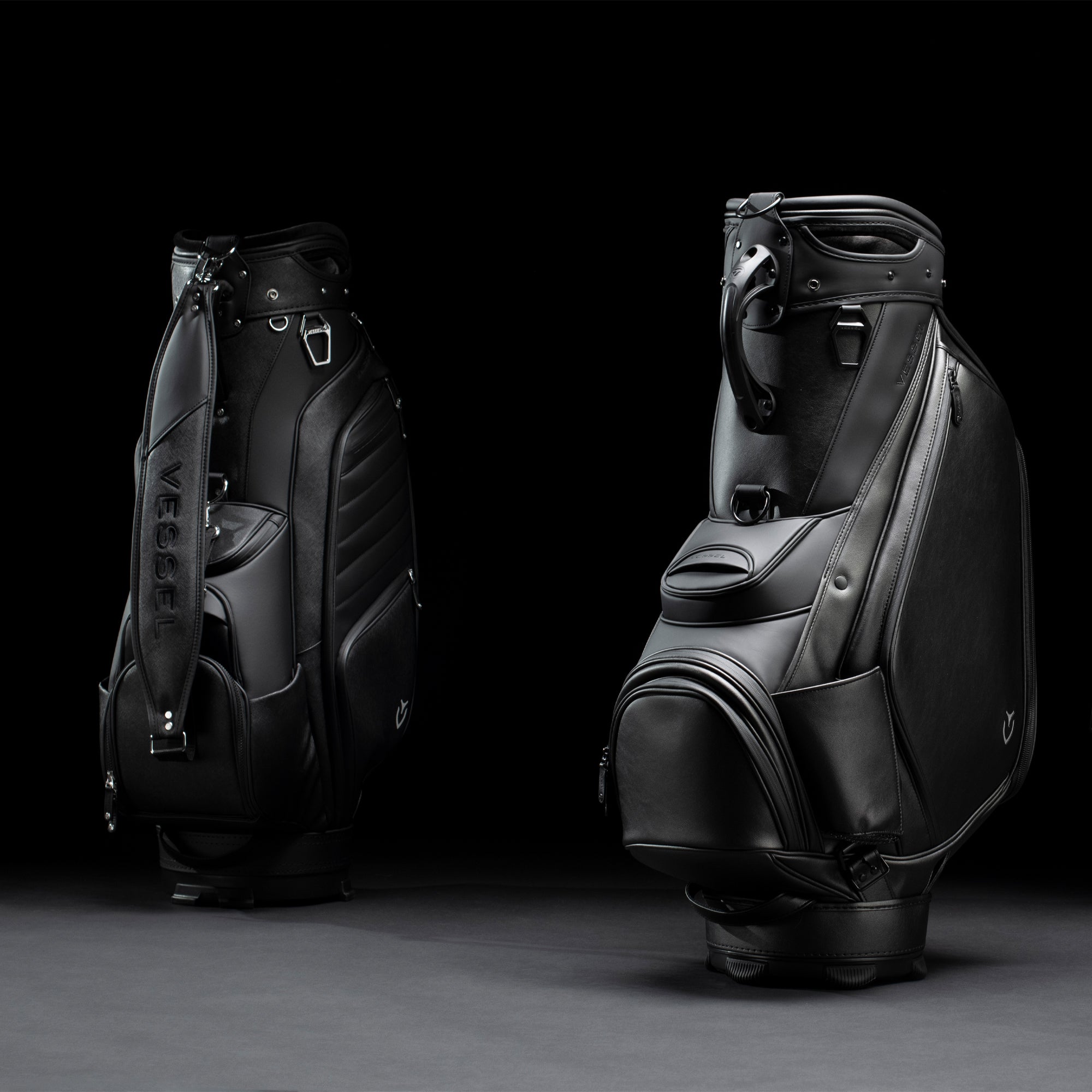 Two black golf staff bags in black studio