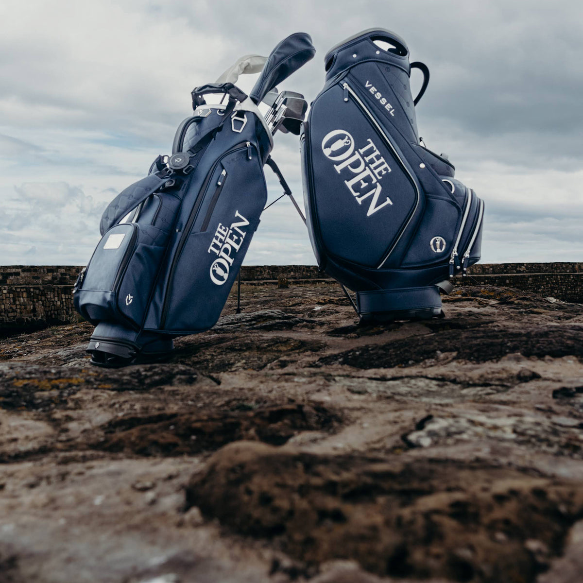 A blue golf stand bag and blue golf staff bag on a rocky bridge.