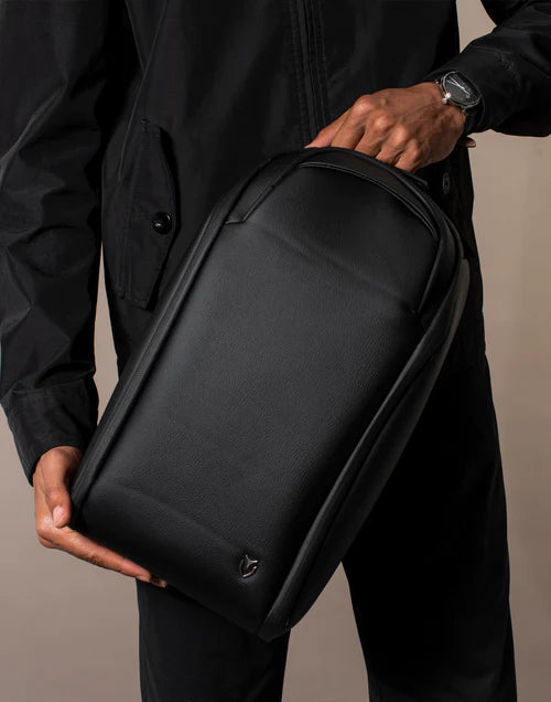 Model wearing black holds a black Voyager Shoe Bag in a brown studio