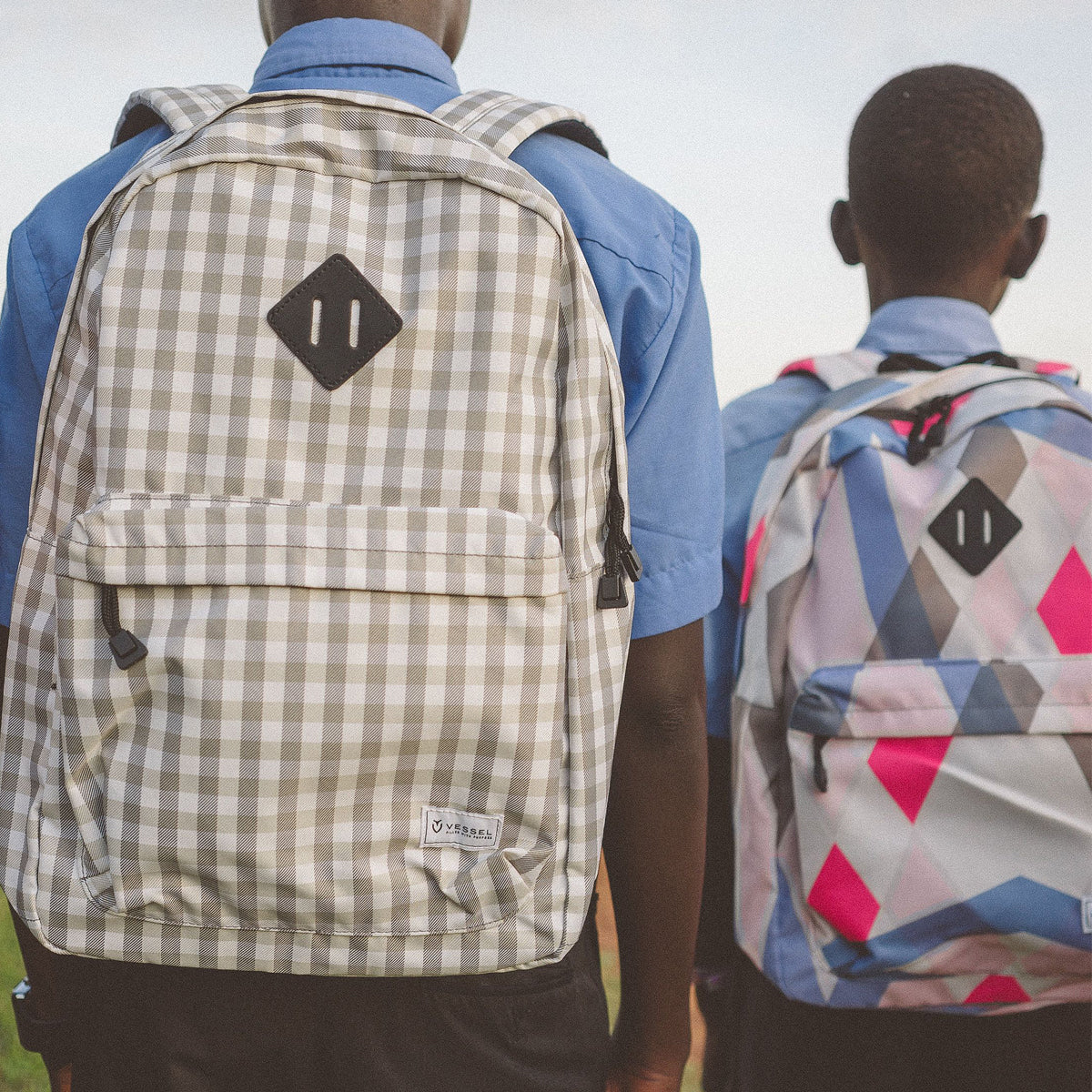 Two students carrying backpacks on their backs while walking outside 