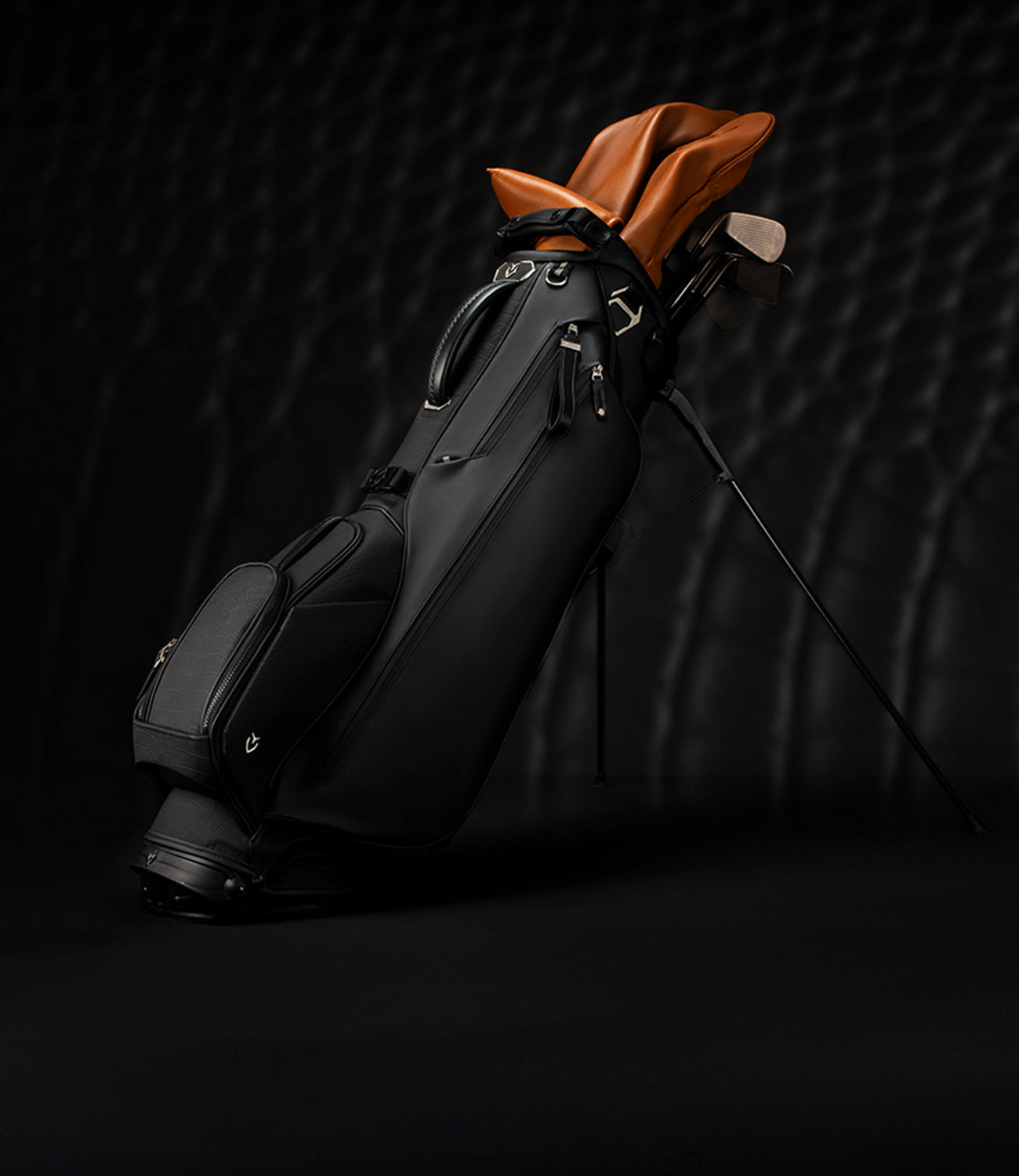 Croc Black Lux Stand golf bag on black background. Bag contains clubs with brown headcovers