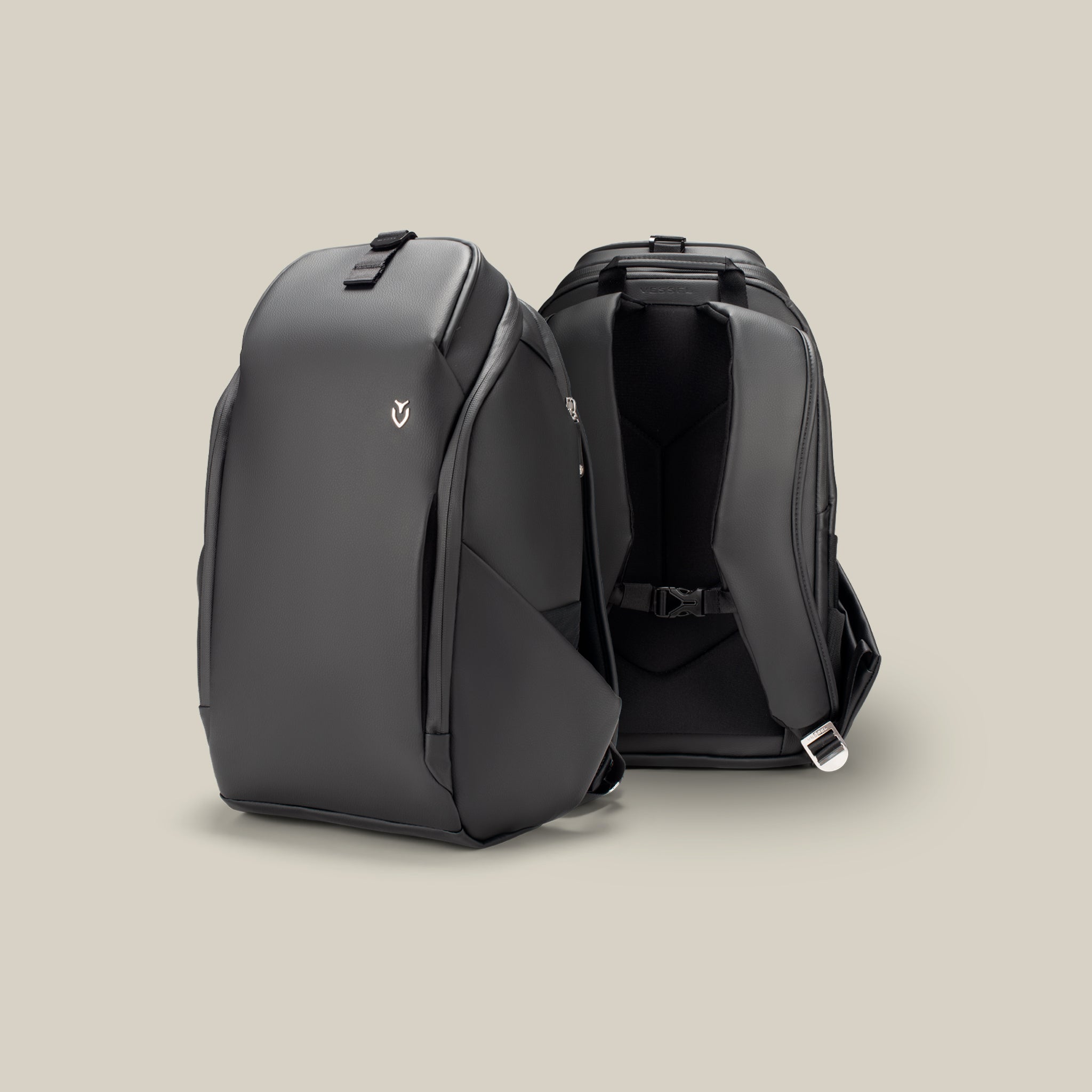 Two black leather backpacks on a taupe background