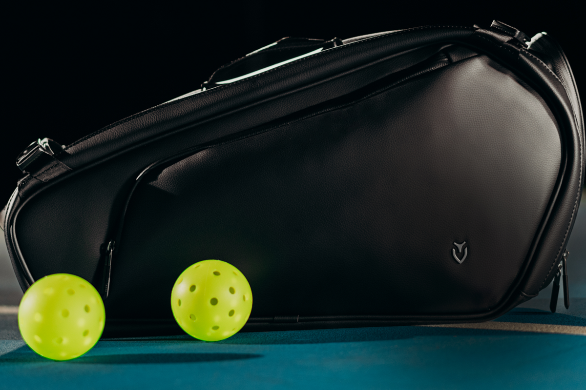 Black leather VESSEL pickleball paddle bag next to pickleballs
