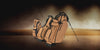 Three brown leather golf bags stacked in front of each other with brown background with smoke
