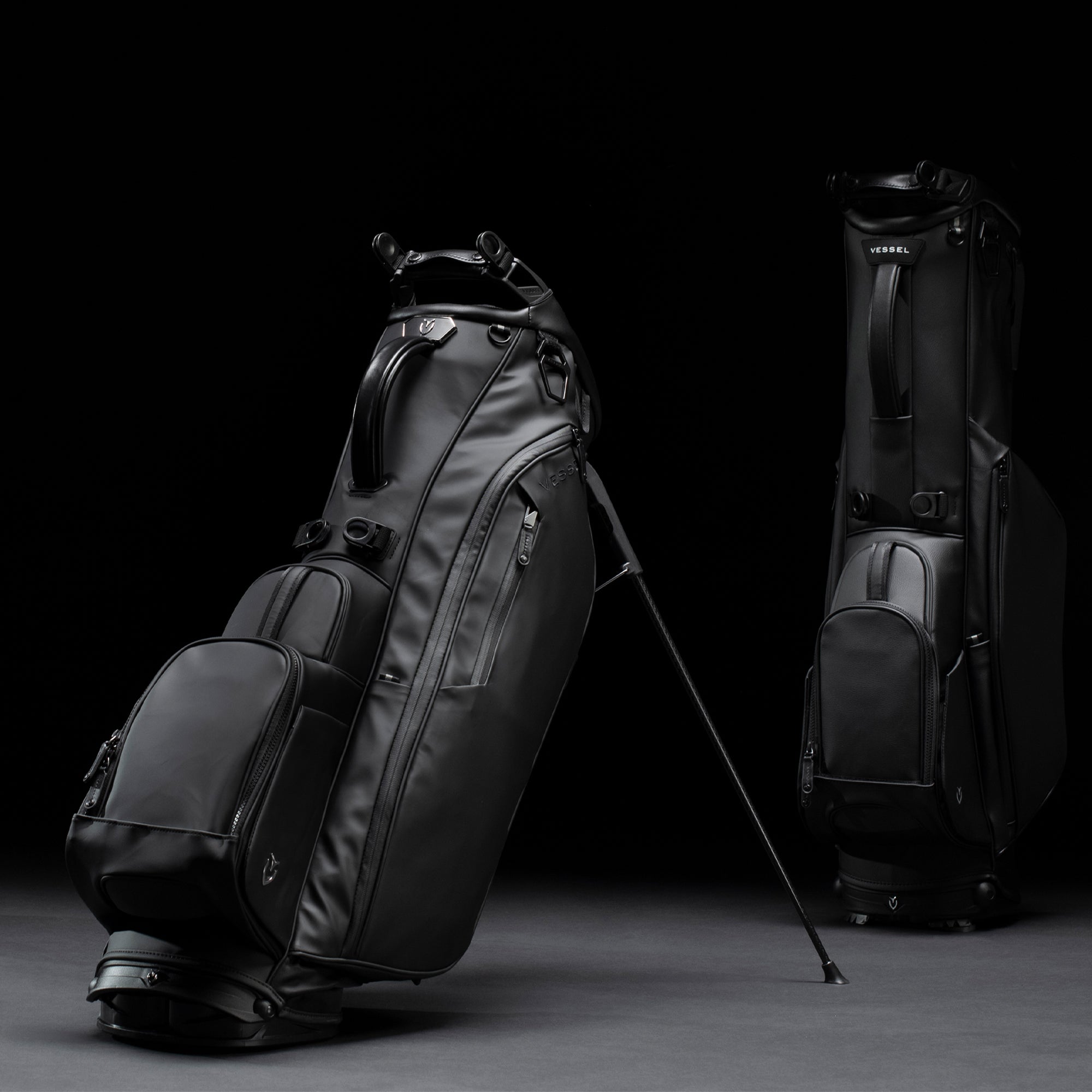 Two black golf stand bags in black studio